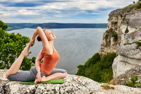 年轻女人做瑜伽锻炼对河岩鸽体式