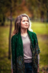 一个年轻女孩与背景秋天公园绿领巾的肖像