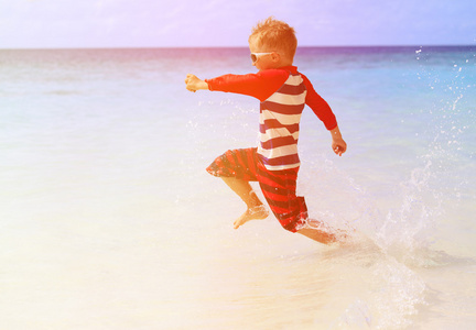 小男孩在海滩上运行溅水