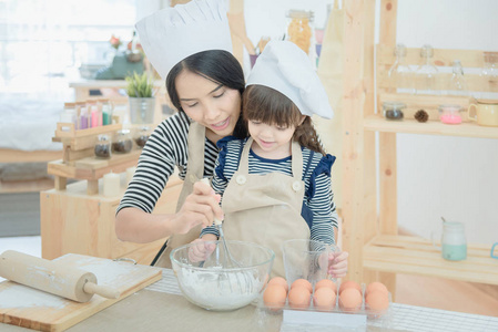 亚洲的母亲和她的女儿正在准备面团度假在厨房做蛋糕