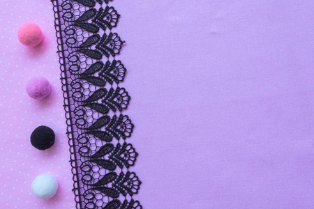 紫色面料和黑色蕾丝。织物和手工花边的背景。毛球白色黑色粉红色紫色