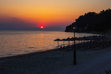 热带海滩遮阳伞 太阳和多彩的夕阳的天空