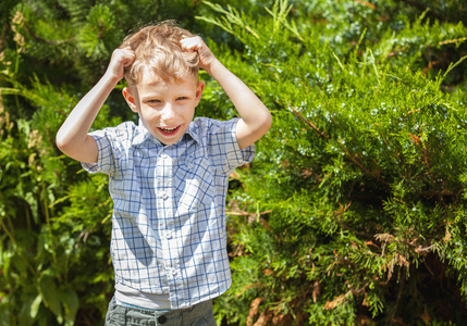 室外肖像的积极的小男孩在阳光灿烂的夏天花园里
