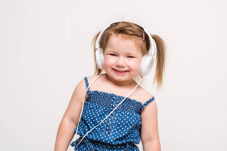 可爱的小女孩，在耳机听音乐使用平板电脑和白色背景上微笑