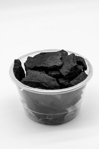 天然木炭在孤立在白色的塑料杯图片