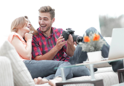 现代年轻夫妇笑和讨论在相机上的照片