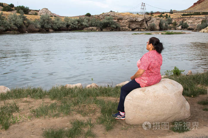 女人坐在河边的石头上照片-正版商用图片0dlqw3-摄图新视界