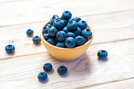在一个木碗蓝莓。顶视图。在一个木制的背景上的成熟和美味蓝莓