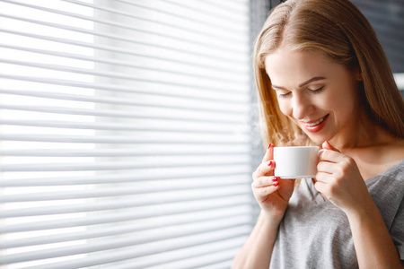幸福的年轻女人满足杯咖啡在风的早晨