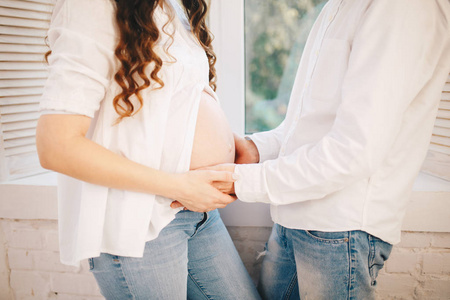 女人打开她怀孕的肚子和男人把他的手放在它