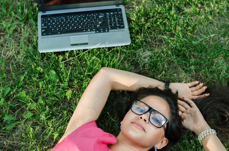 一台笔记本电脑，躺在草地上的漂亮女孩