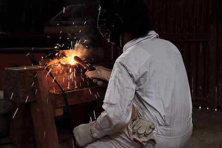 后视图与火炬和防护面具钢的火花在工厂焊接专业焊工人。工业的概念