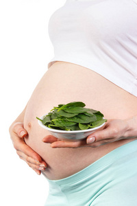 女人怀孕举着碧绿的菠菜中碗，含铁在怀孕期间的健康营养