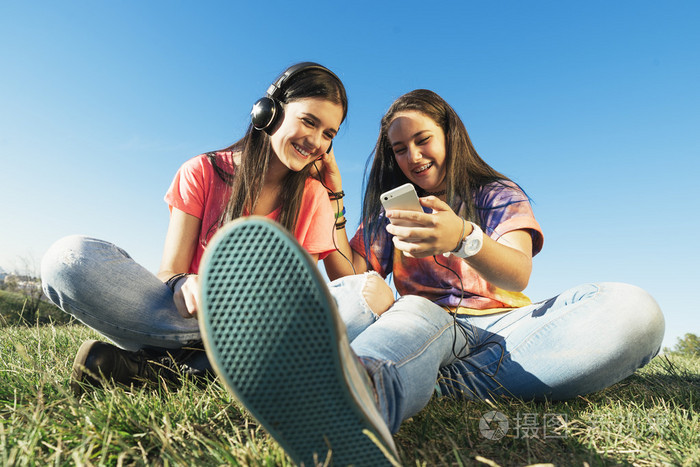 快乐的青少年朋友,夏天在公园听音乐
