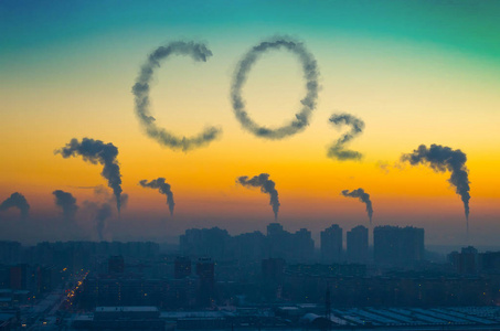 晚上在日落时从烟囱排放黑烟的城市工业景观的视图。铭文 Co2