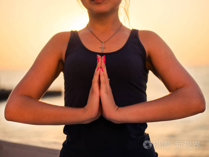 肖像的漂亮的女人在运动服练瑜伽与双手合十冥想呼吸放松坐在海洋沙滩