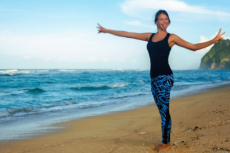 练习瑜伽在海滩上的看日出的年轻女人