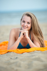 在海滩上晒日光浴的年轻女士。美丽的女人在摆姿势