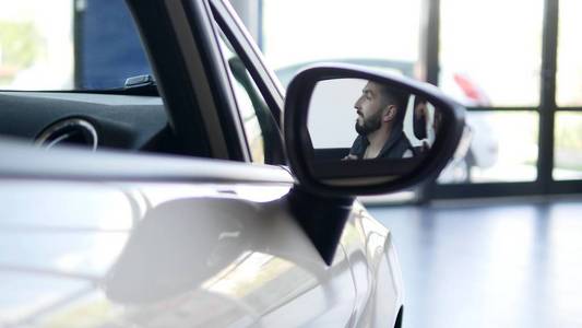 酷微笑快乐的人在镜子中显示汽车关键