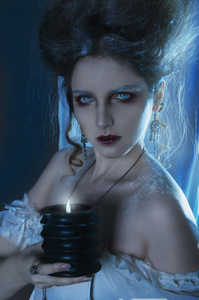 画像的一个美丽的女孩鬼，巫婆新娘穿白色衣服拿在手中燃烧的蜡烛黑