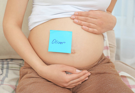 孕妇的肚子，特写的贴纸。选择婴儿名字的概念