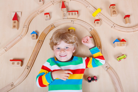 一个金发小孩在室内玩木火车