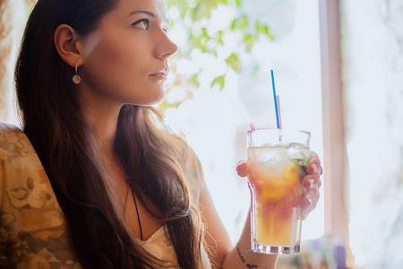 生活方式的黑发女孩在咖啡馆里持有类鸡尾酒或柠檬水的肖像