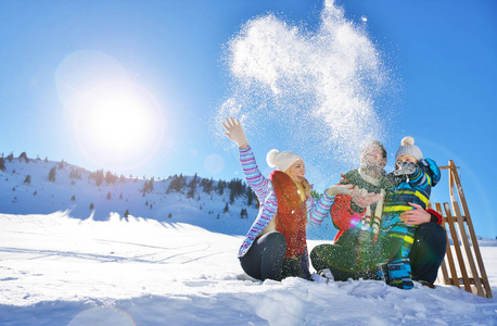 幸福年轻的家庭，在新鲜的雪打美丽晴朗的冬日户外性质