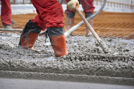 工人用耙子的红靴子的夷为平地的混凝土