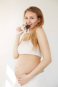 美味与健康而怀孕的不确定选择。女人在她的第二孕期吃一块巧克力