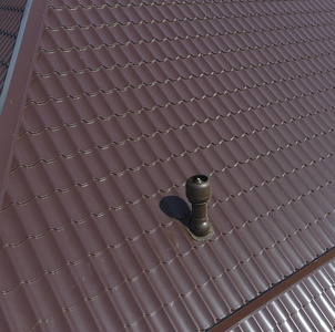金属屋顶上的通风管道。瓦楞纸板的屋顶。金属型材波纹形屋面