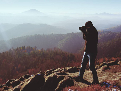 专业摄影师的照片带镜相机的岩峰上。梦幻般的雾