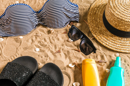 夏季比基尼和配件时尚沙滩 海滩比基尼夏季服装和海砂作为背景，顶视图的概念