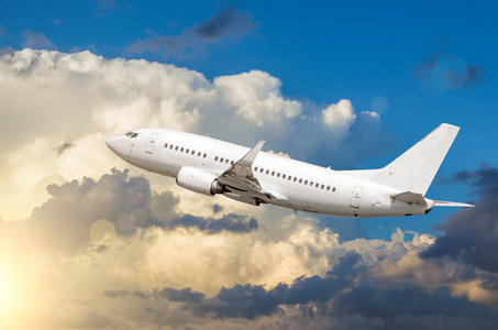 白色的客运飞机起飞的积云的背景在日落时分