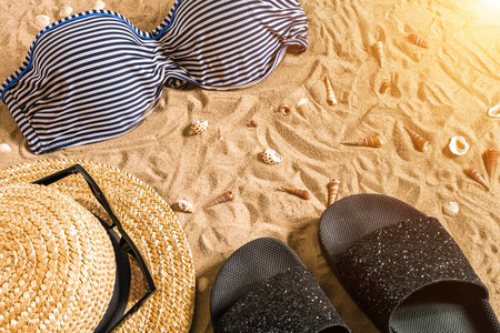 夏季比基尼和配件时尚沙滩 海滩比基尼夏季服装和海砂作为背景，顶视图的概念