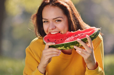 幸福的年轻女人，在公园里吃西瓜