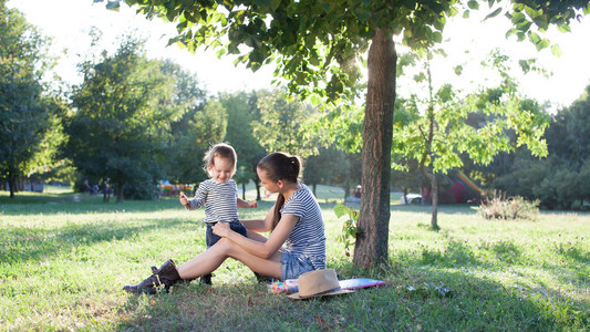 母亲和孩子坐在树下，在暑假期间