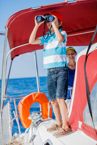 男孩船长和他的姐姐在船上的游艇航行在夏天巡航。冒险旅行，家庭度假游艇与孩子