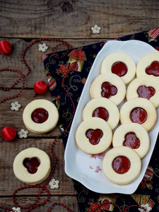 传统的自制圣诞饼干林茨饼干充满红色的果酱，木制的背景上。选择性的焦点