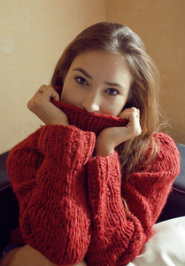 年轻漂亮的女人穿着红色毛衣和围巾在她的脸上微笑在家中, 冬季积极