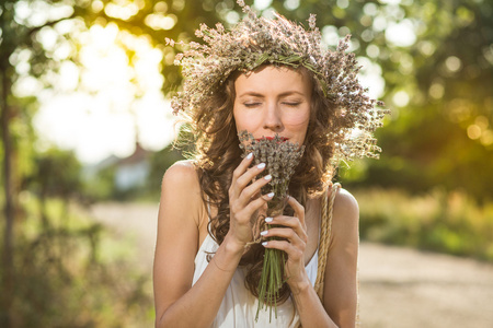 年轻美丽的女子和薰衣草花环上的头靠在阳光明媚的夏日