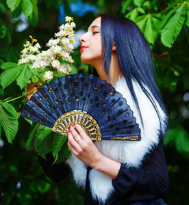 微笑的年轻女子闻着美丽的花白花