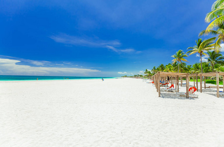 热带的白色沙滩和绿松石的宁静海洋，人们放松在可可岛古巴岛的背景与邀请看视野非常好