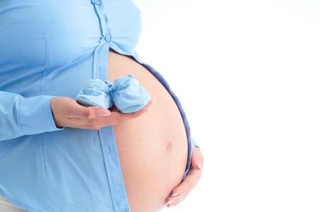 怀孕的妇女，她手里拿着小蓝婴儿鞋