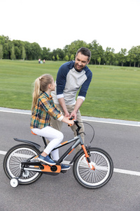 骑在自行车上的父亲教学女儿