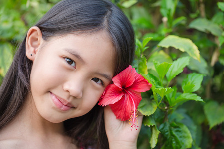 小的亚洲女孩，微笑着与中国在花园里玫瑰