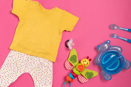 婴儿的衣服和配件在粉红色的背景上。顶视图