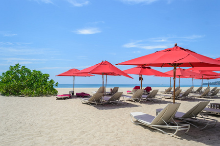 沙滩椅和红伞与蓝蓝的天空，在泰国普吉岛邦涛海滩上
