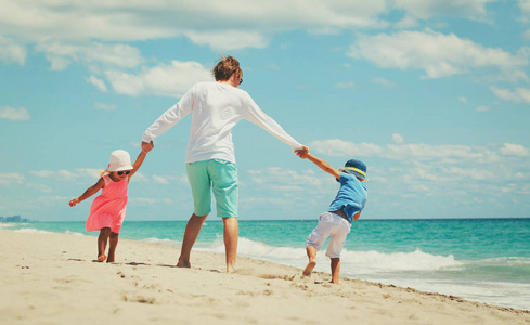 父亲与小儿子和女儿在沙滩上玩