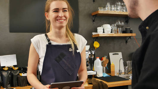 华丽的女店员考虑的一款平板电脑的客户订单和微笑的画像